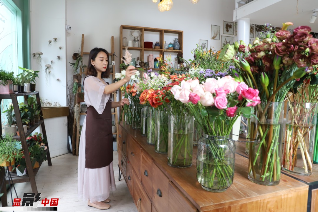 王黎媛是一名河南姑娘，在昆明念完大學(xué)后，就再也舍不下春城的藍(lán)天陽(yáng)光、青山碧水，更舍不下這里的四時(shí)繁花，于是就干脆留了下來(lái)，成了一名媒體人。2017年的時(shí)候又毅然辭去工作，創(chuàng)業(yè)開(kāi)起了花店，成了都市里的一名“花房姑娘”。圖為王黎媛在自己的花店中整理鮮花。新華網(wǎng) 周亞平/攝 念新洪/文